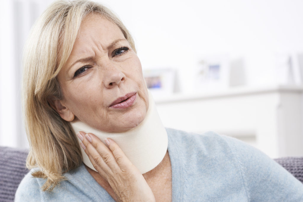 Mature Woman Suffering from Whiplash Wearing Surgical Collar In Pain