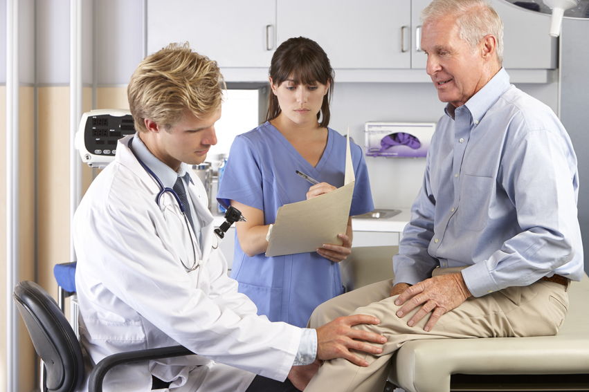 Doctor Examining Male Patient With Knee Pain